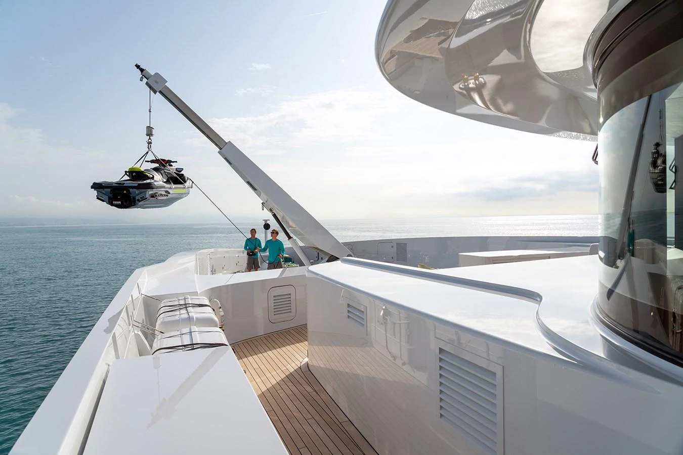 The yacht's deck features a crane lifting a jet ski, with crew members overseeing the operation. aboard SOLEMATES Yacht for Sale