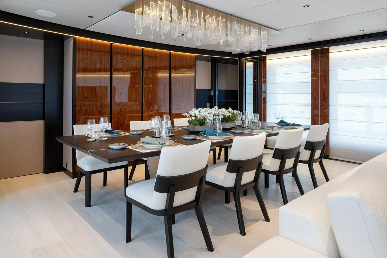The yacht's dining area features an elegant table set for a formal meal, surrounded by plush chairs and accentuated by modern lighting. aboard SOLEMATES Yacht for Sale