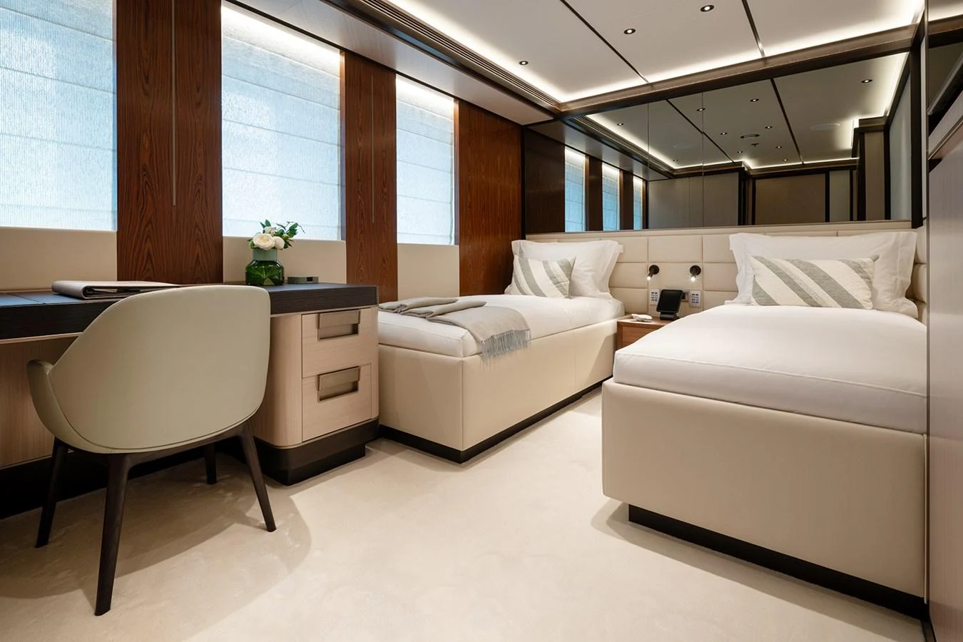 The guest stateroom features twin beds, a writing desk, and modern decor. aboard SOLEMATES Yacht for Sale