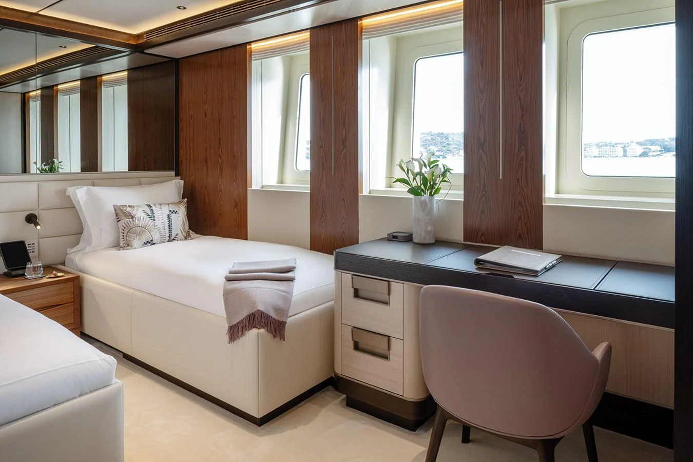 A luxurious stateroom featuring a comfortable bed, a desk, and large windows with a scenic view. aboard SOLEMATES Yacht for Sale