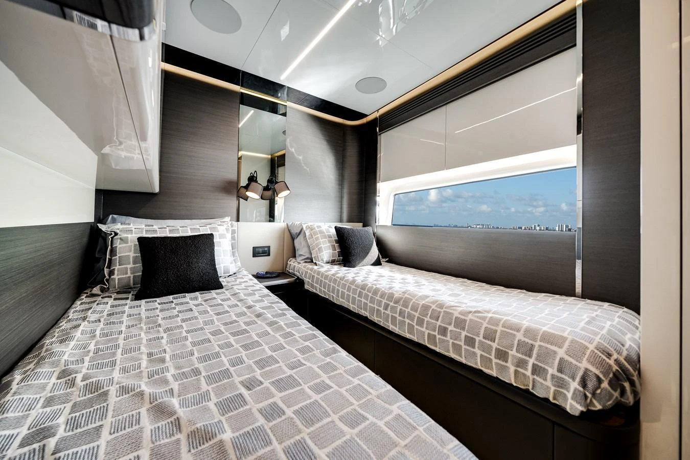 The guest stateroom features twin beds with modern decor and a large window offering a scenic view. aboard PARTNERSHIP V Yacht for Sale