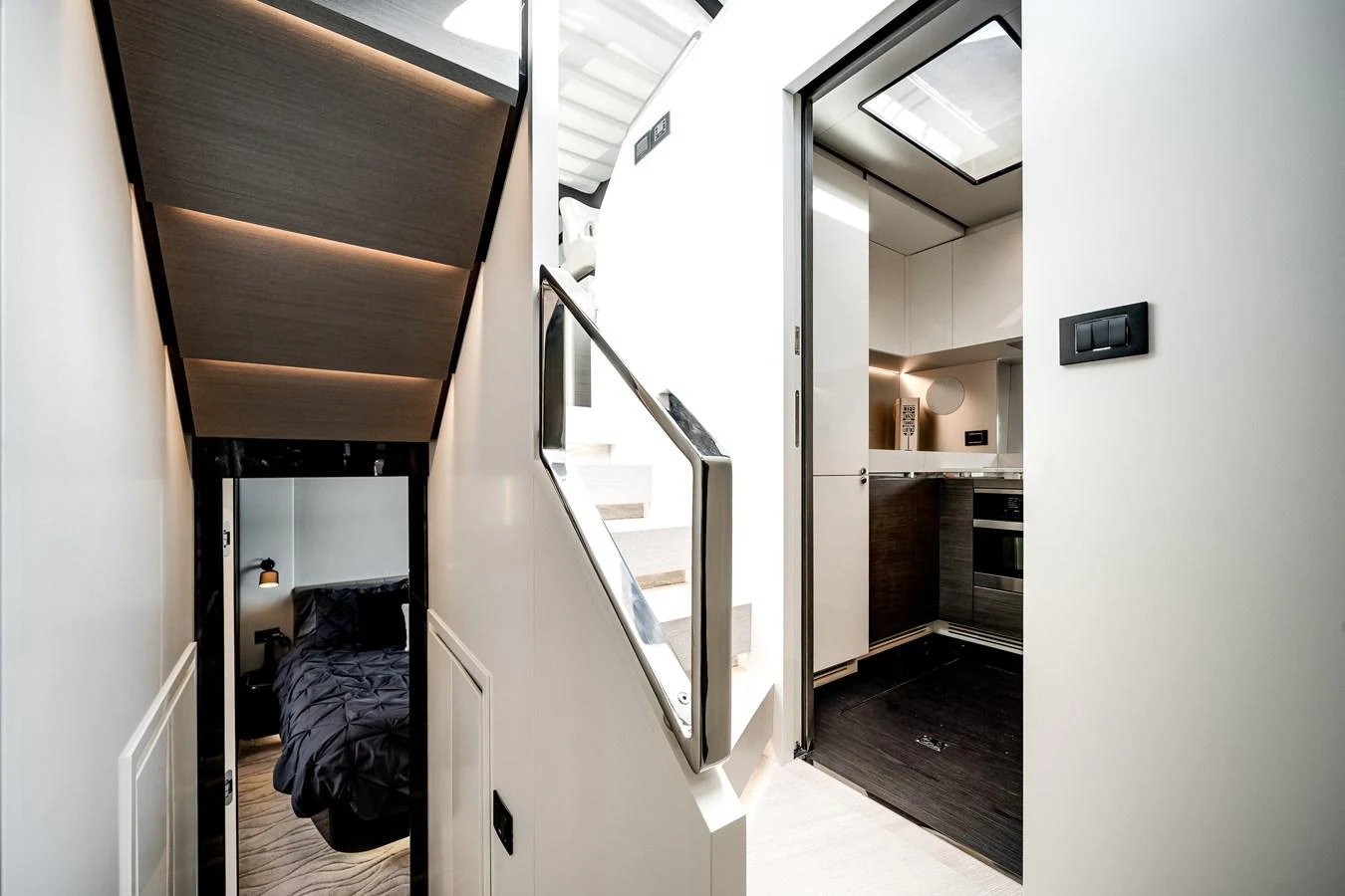 A modern yacht interior featuring a sleek staircase leading to different levels and a cozy bedroom. aboard PARTNERSHIP V Yacht for Sale