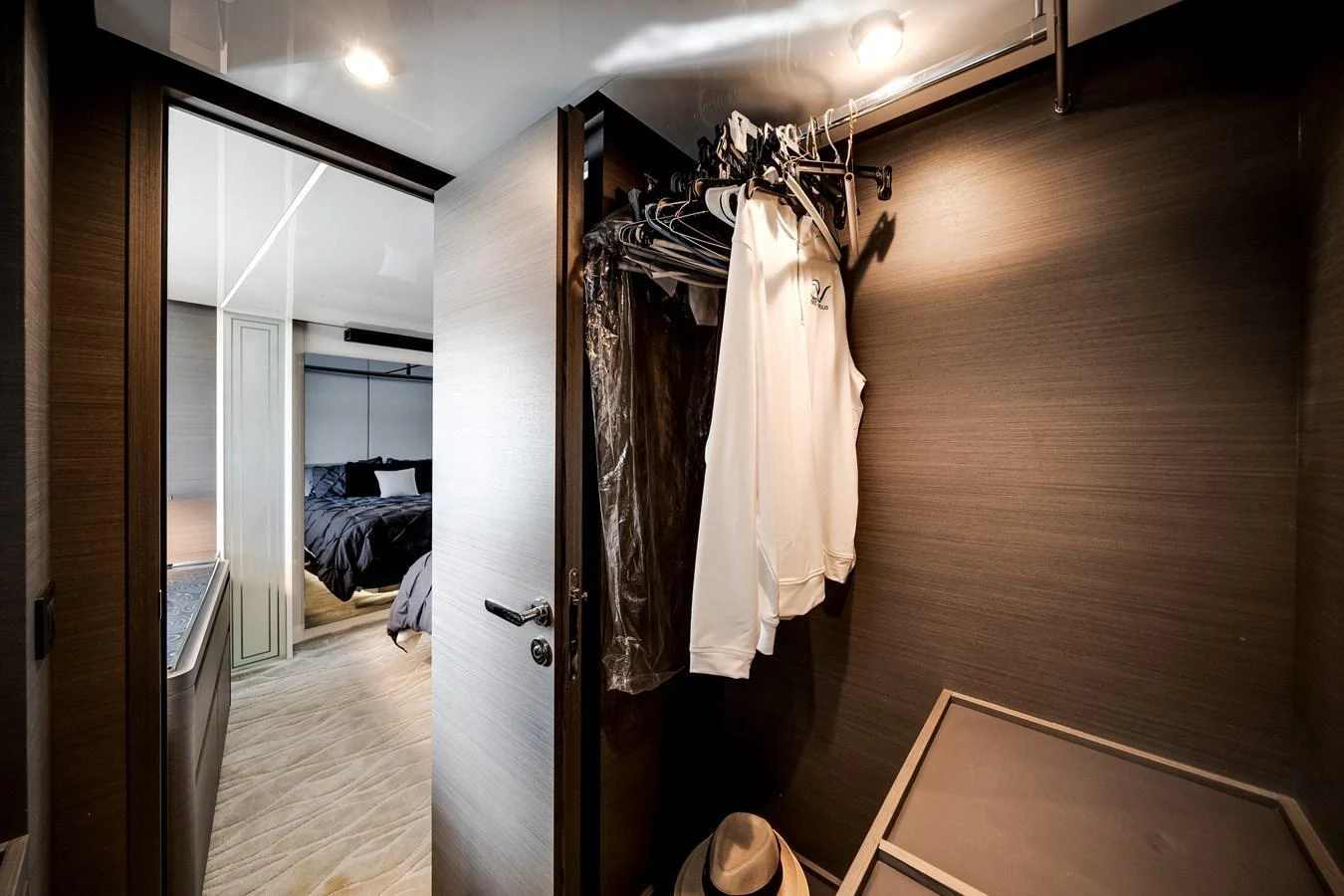 A well-organized closet space with hanging clothes and a view into a luxurious bedroom. aboard PARTNERSHIP V Yacht for Sale