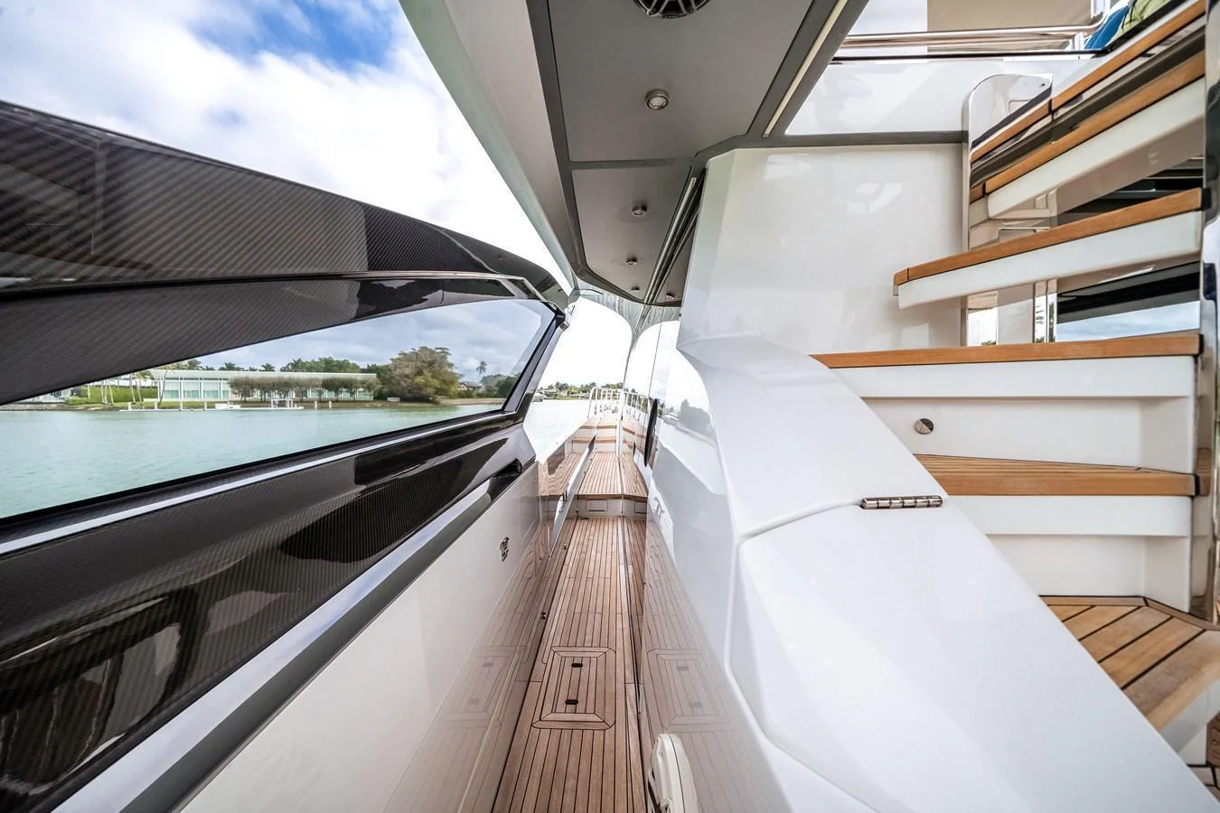 The side deck offers a sleek passageway with modern design elements and wooden steps leading to the upper deck. aboard PARTNERSHIP V Yacht for Sale