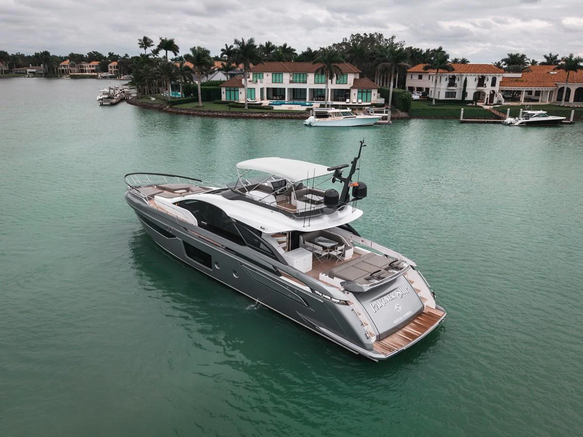 A sleek yacht cruises through a serene waterfront neighborhood, showcasing its modern design and spacious deck. aboard PARTNERSHIP V Yacht for Sale