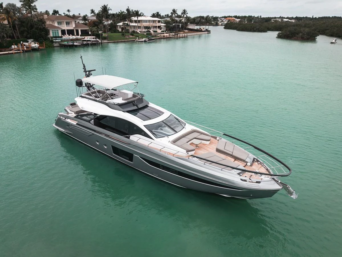 A sleek and modern yacht glides gracefully on tranquil turquoise waters near a luxurious waterfront community. aboard PARTNERSHIP V Yacht for Sale