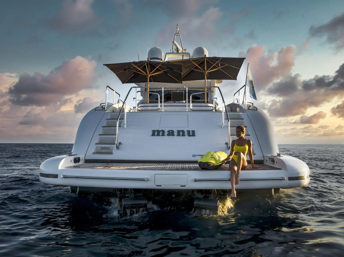 The yacht's aft deck features a relaxing area with a woman enjoying the serene ocean view. aboard MANU Yacht for Sale