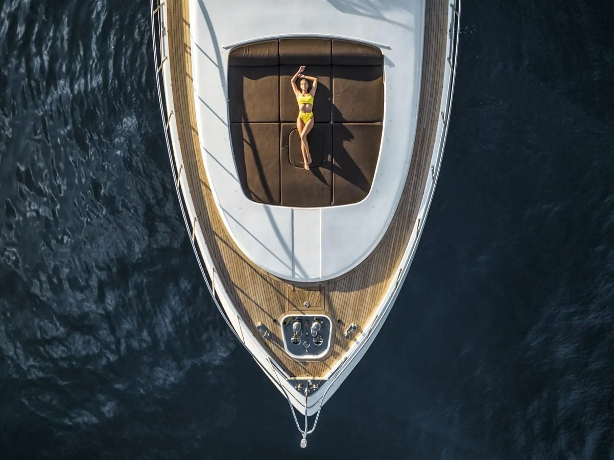 A luxurious foredeck with a sunbathing area, captured from above, showcasing the yacht's sleek design and inviting relaxation space. aboard MANU Yacht for Sale
