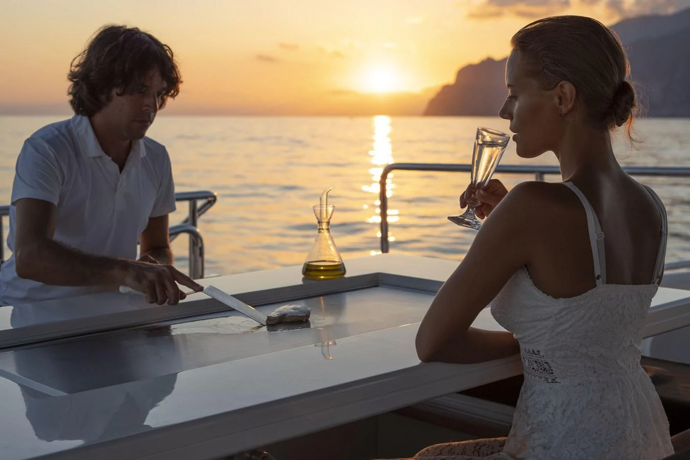 An elegant outdoor bar setup on the yacht at sunset, featuring a couple enjoying drinks. aboard MANU Yacht for Sale