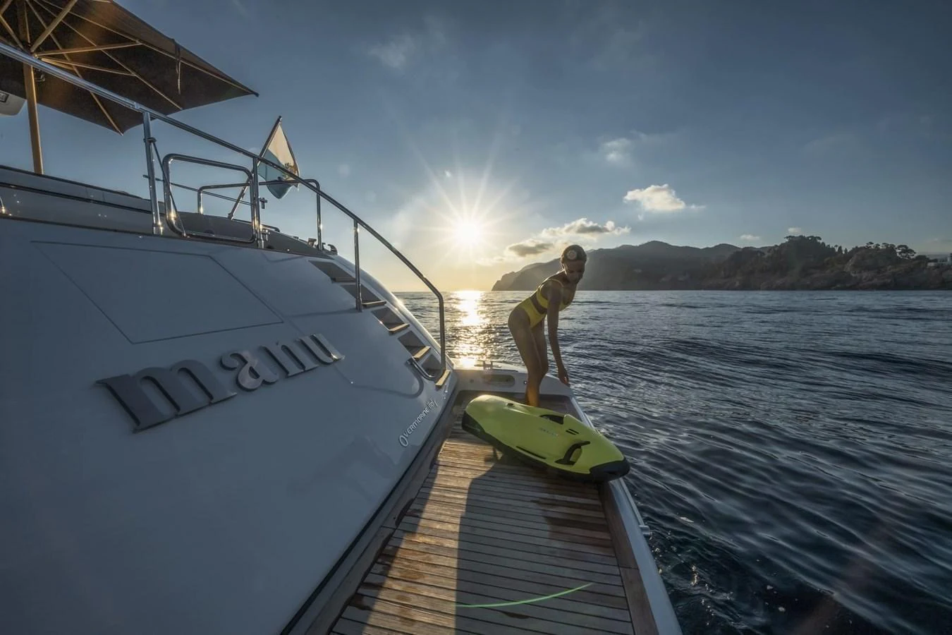 A person prepares to enter the water from the yacht's swim platform at sunset. aboard MANU Yacht for Sale