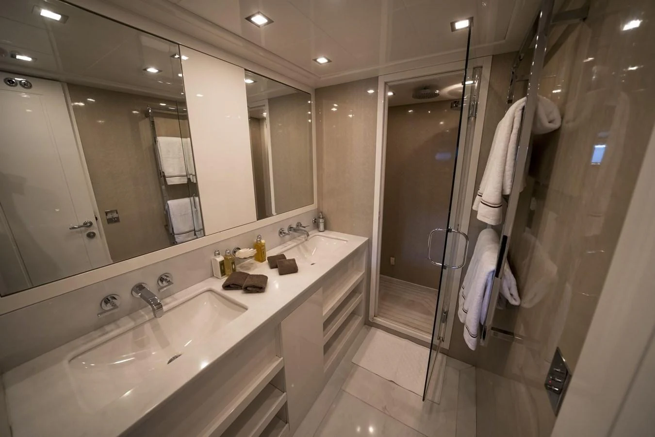 The yacht's bathroom features a sleek design with a spacious shower and double sinks. aboard MANU Yacht for Sale