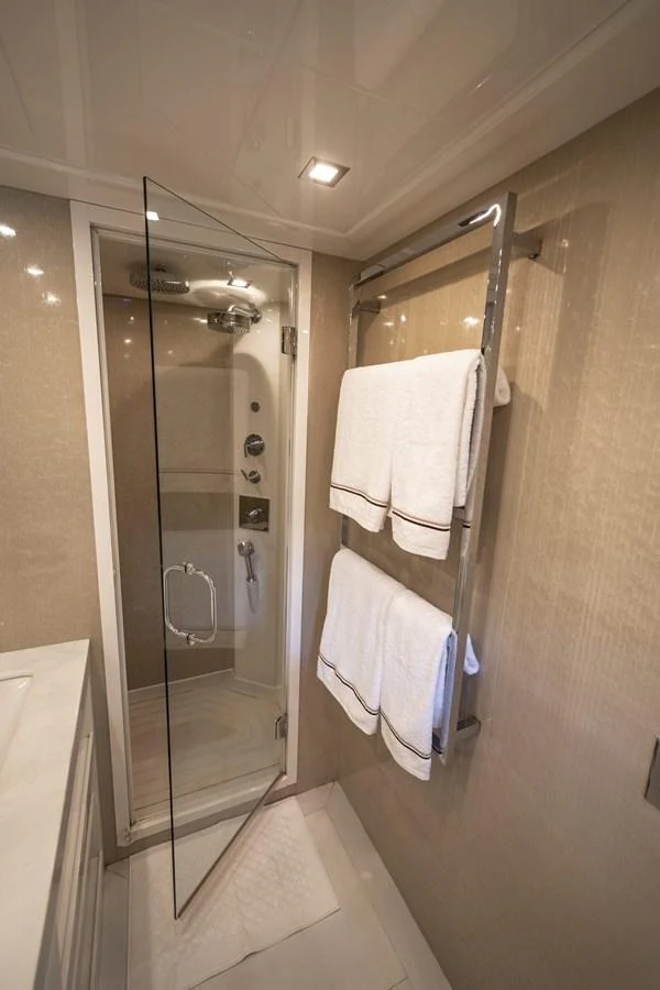 A luxurious yacht bathroom featuring a glass-enclosed shower and neatly arranged towels. aboard MANU Yacht for Sale