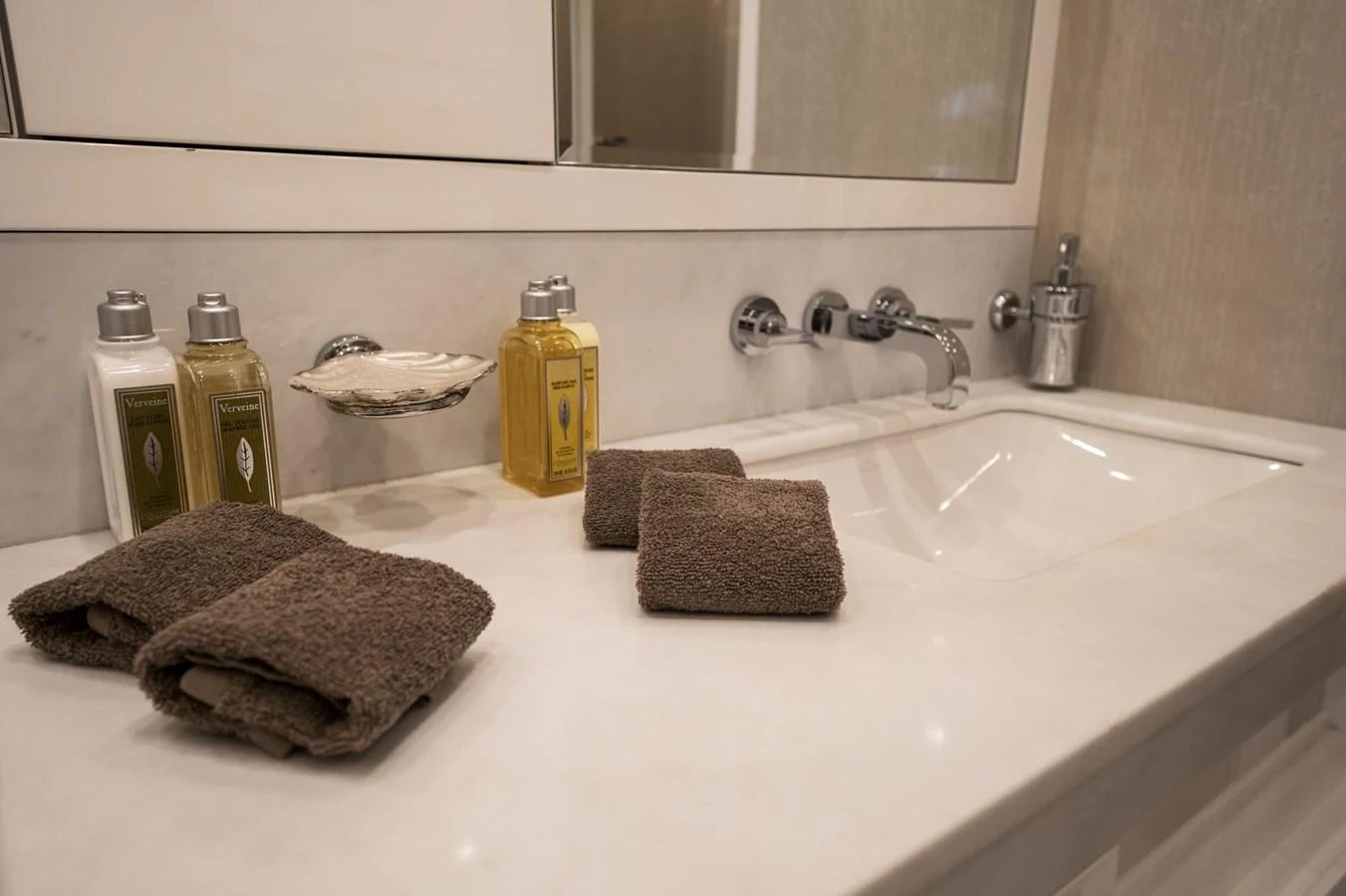 The bathroom features a sleek countertop with elegant toiletries and plush towels. aboard MANU Yacht for Sale