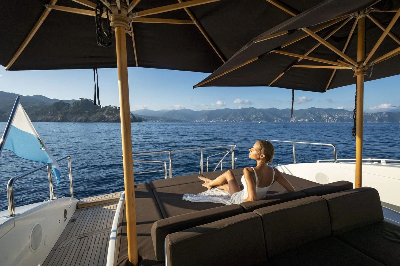 A serene sundeck with comfortable lounging areas under large umbrellas, offering stunning ocean views. aboard MANU Yacht for Sale
