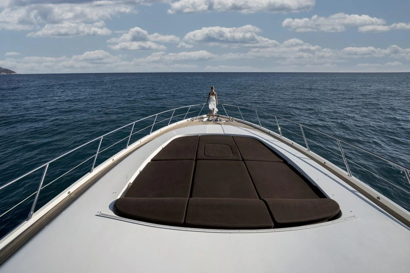 A luxurious yacht cruising on open waters with a person standing at the bow. aboard MANU Yacht for Sale