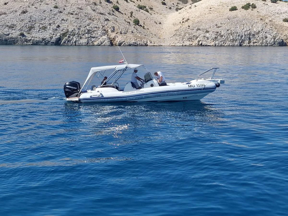 A sleek motor yacht cruises along a serene coastline, showcasing its streamlined design and powerful outboard engine. aboard LADY TATIANA Yacht for Sale