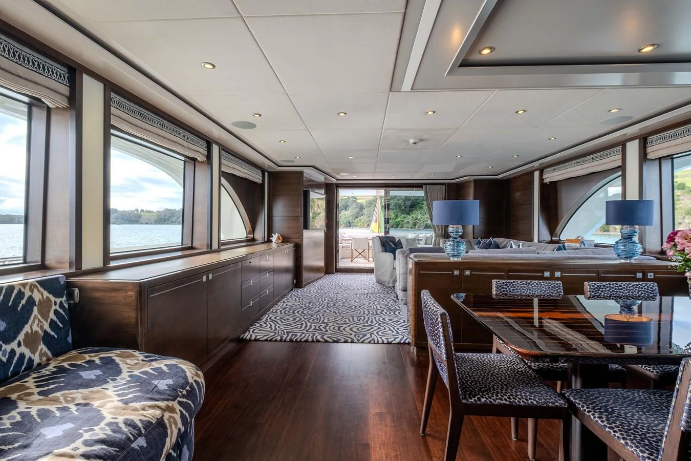 a large living room with a wood table and chairs aboard MAHALO Yacht for Sale