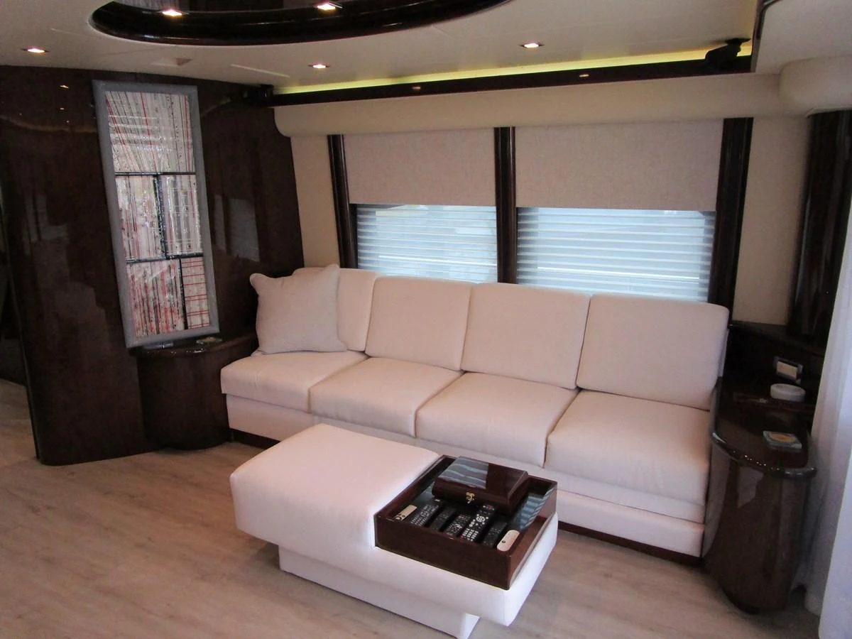The salon features a comfortable white sofa with a matching ottoman and sleek wooden accents. aboard SHORE GIRL Yacht for Sale