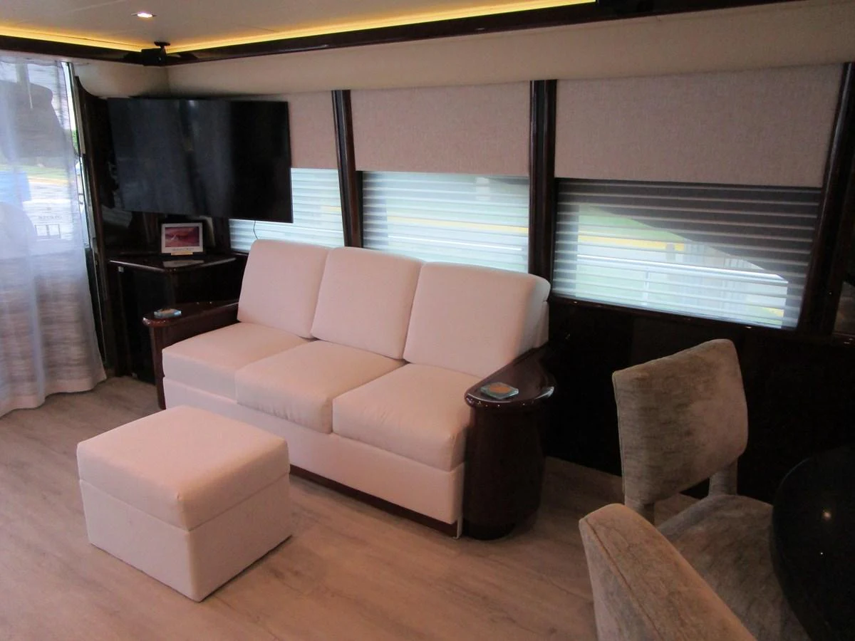 The yacht's salon features a comfortable white sofa, a matching ottoman, and a flat-screen TV, creating a cozy and inviting atmosphere. aboard SHORE GIRL Yacht for Sale