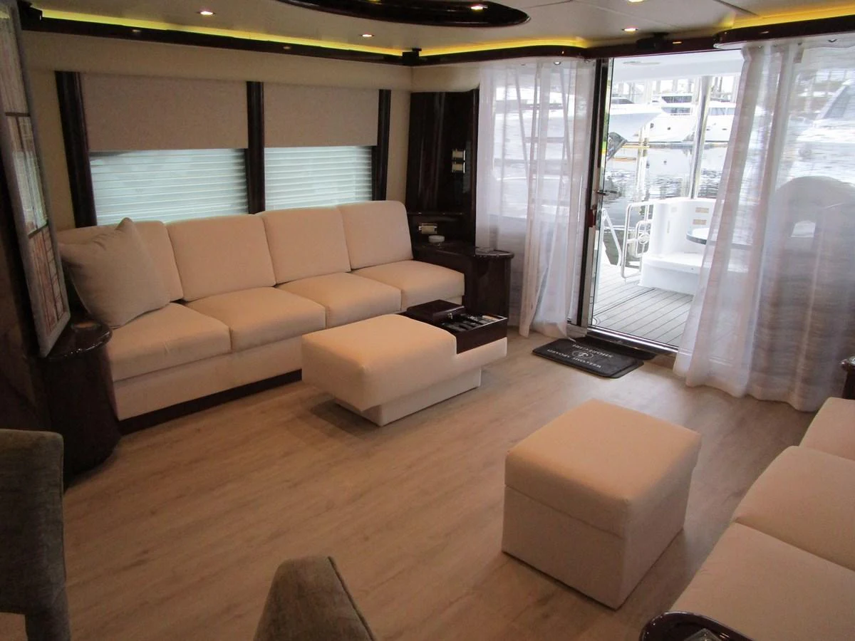 The salon features comfortable seating with a view of the marina through large windows and a sliding door. aboard SHORE GIRL Yacht for Sale