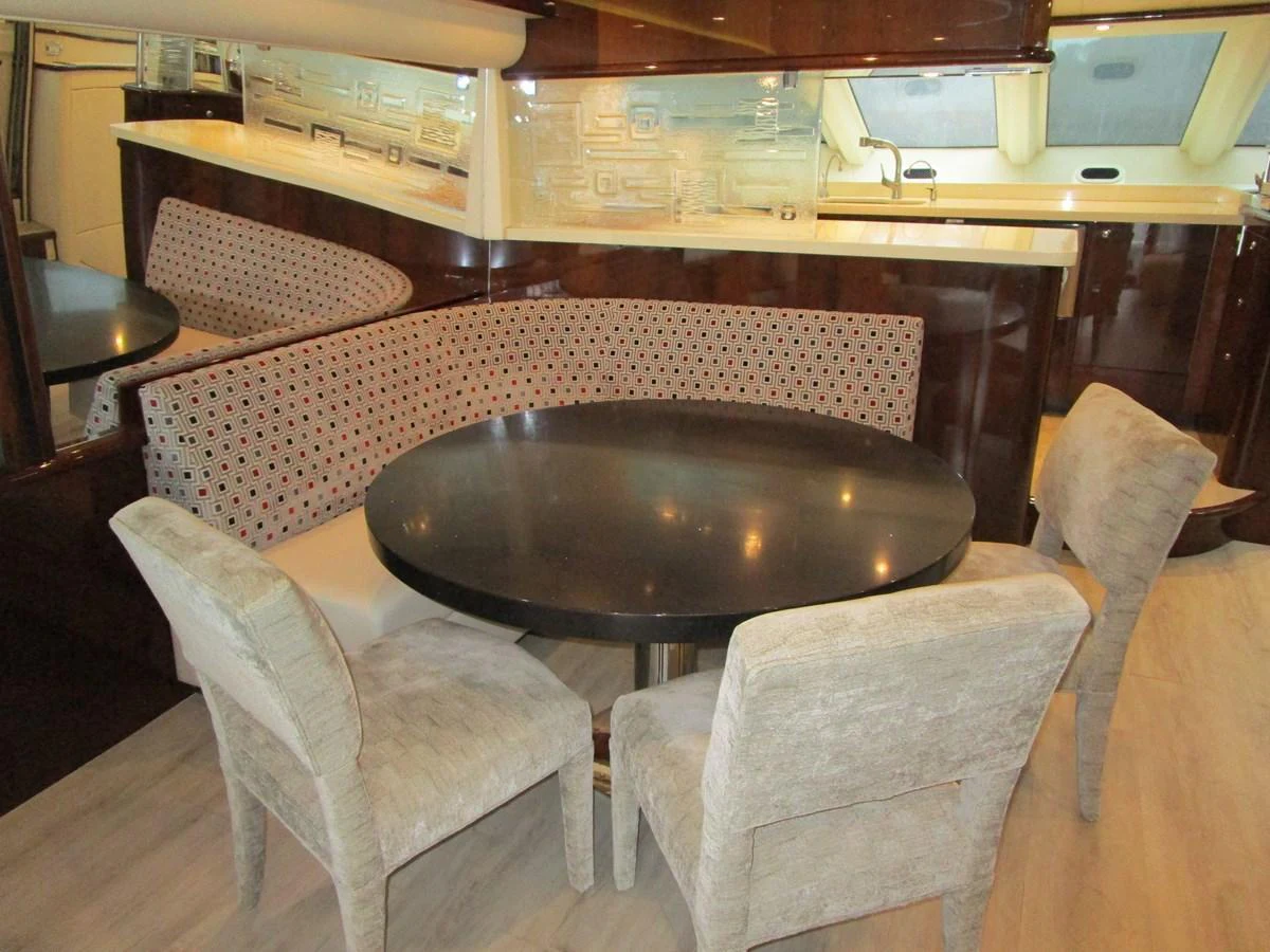 The yacht's dining area features a round table with upholstered chairs and a built-in bench, creating a cozy and elegant space for meals. aboard SHORE GIRL Yacht for Sale