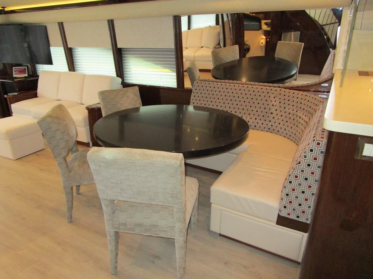 The yacht's dining area features a round table with a mix of upholstered chairs and a cushioned bench, creating a cozy and elegant setting. aboard SHORE GIRL Yacht for Sale