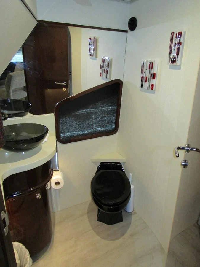 A modern yacht bathroom featuring a sleek black toilet and matching sink with contemporary decor. aboard SHORE GIRL Yacht for Sale