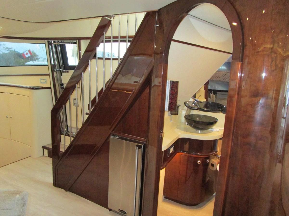 The yacht's interior features a polished wooden staircase leading to an upper deck, complemented by modern fixtures and a sleek design. aboard SHORE GIRL Yacht for Sale