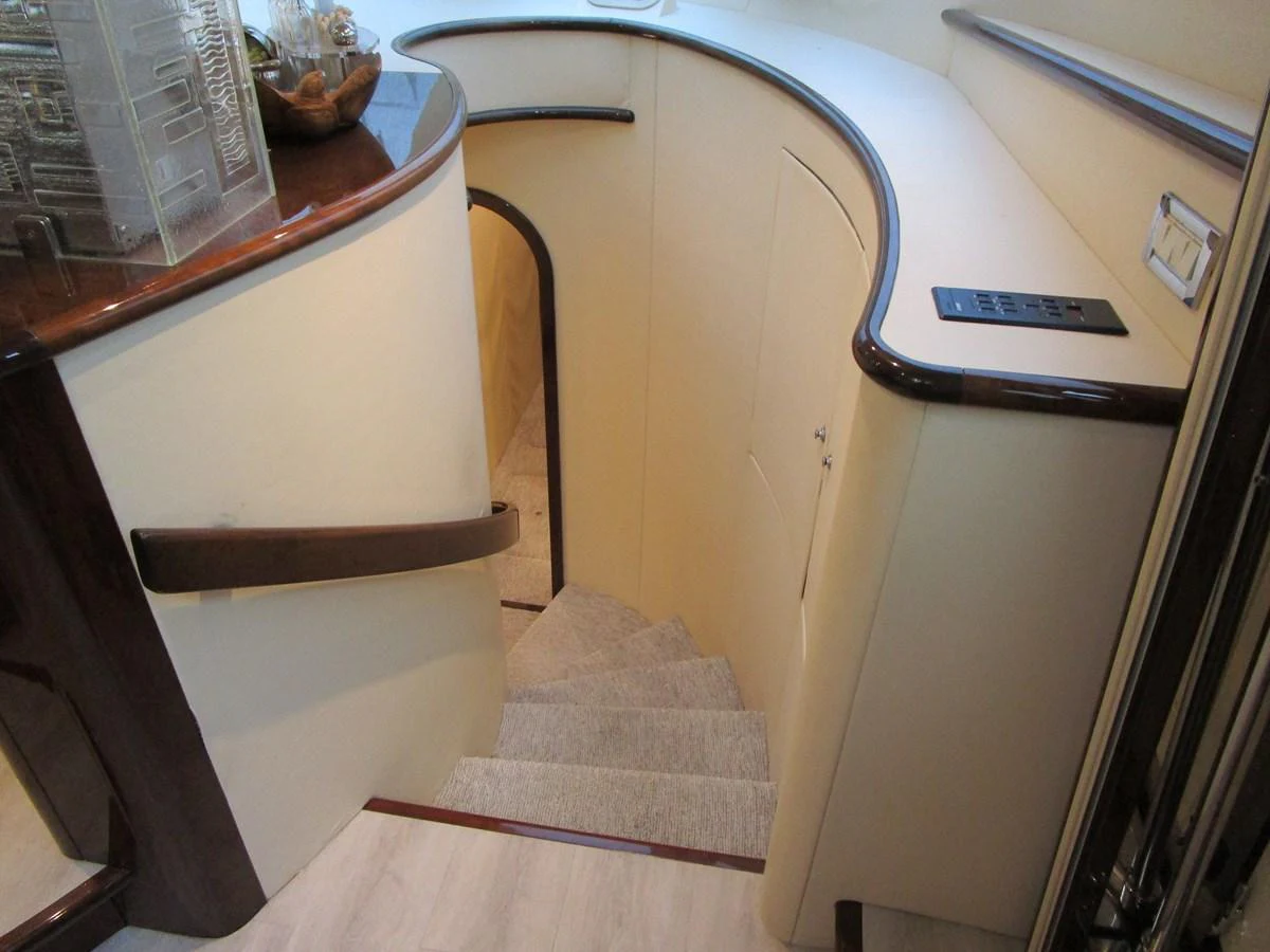 The image showcases a stylish interior staircase with elegant wood accents and soft lighting. aboard SHORE GIRL Yacht for Sale