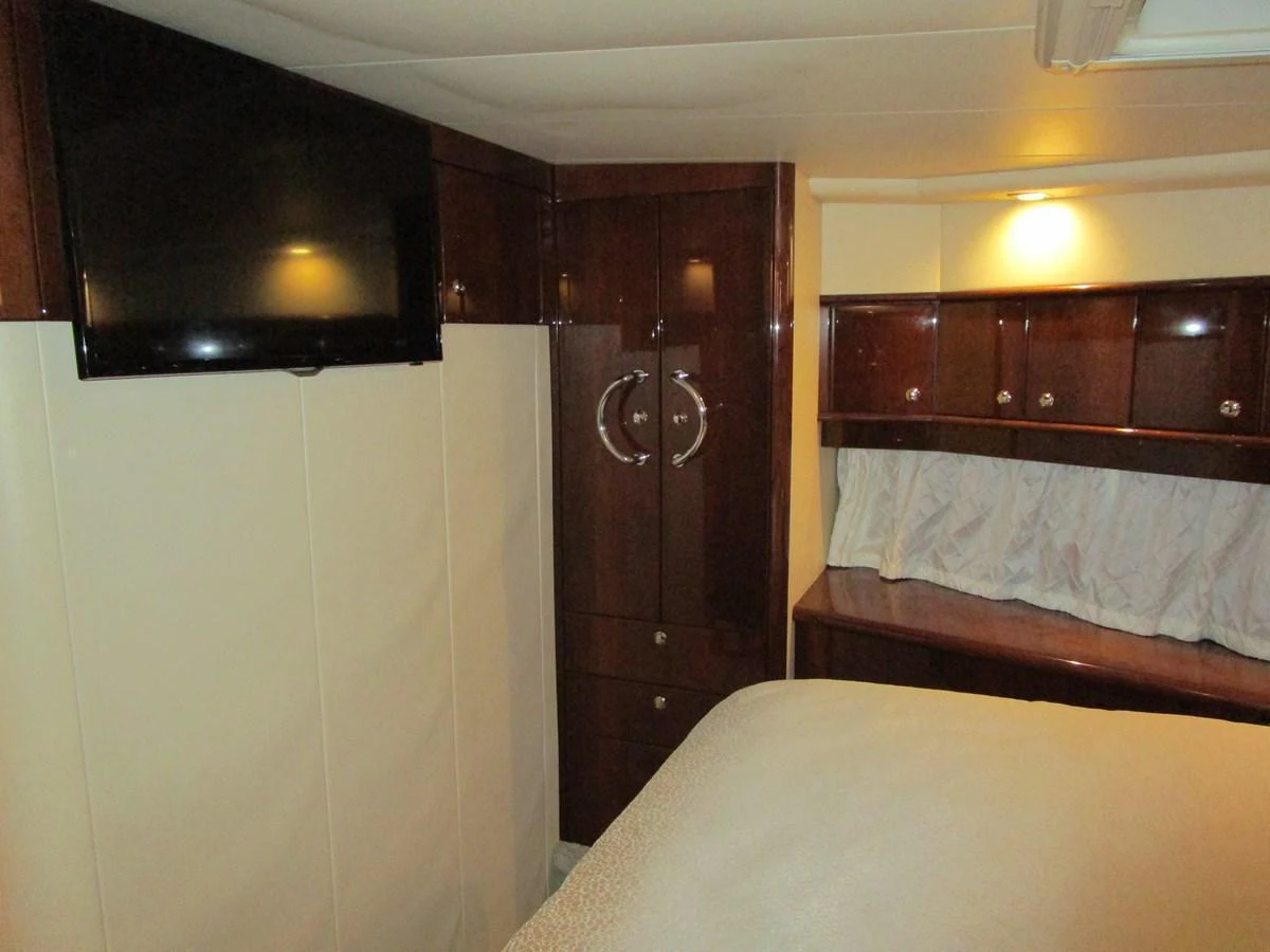 A cozy stateroom featuring a mounted television and elegant wooden cabinetry. aboard SHORE GIRL Yacht for Sale