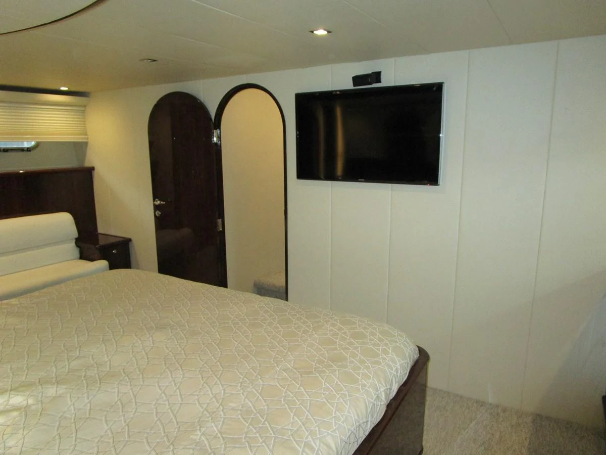 The stateroom features a comfortable bed, a wall-mounted TV, and elegant wooden accents. aboard SHORE GIRL Yacht for Sale