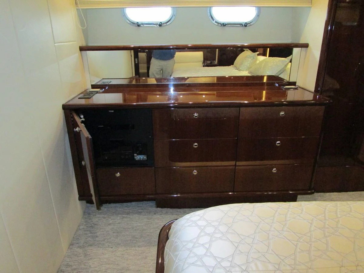 The image showcases a luxurious stateroom with elegant wooden cabinetry and a plush bed. aboard SHORE GIRL Yacht for Sale