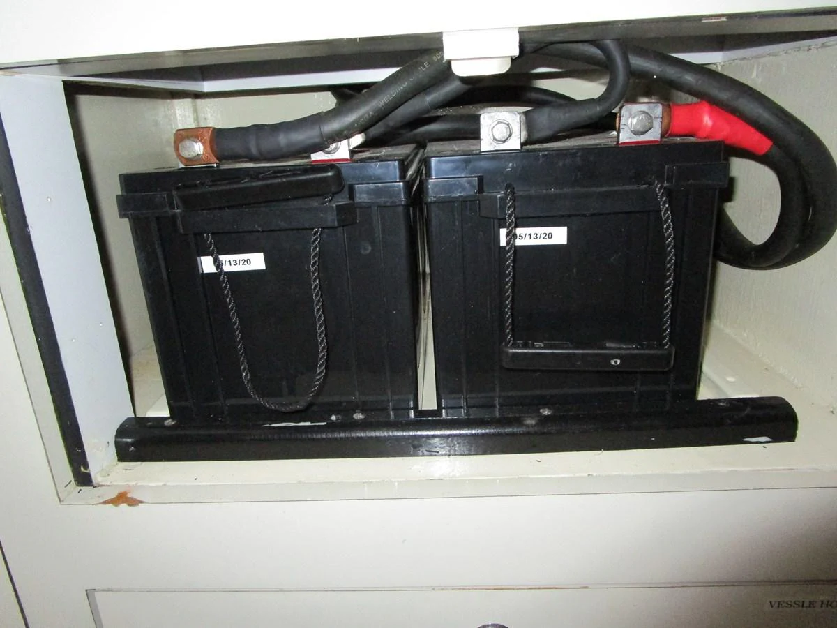 The image shows the yacht's battery compartment with two black batteries securely installed. aboard SHORE GIRL Yacht for Sale