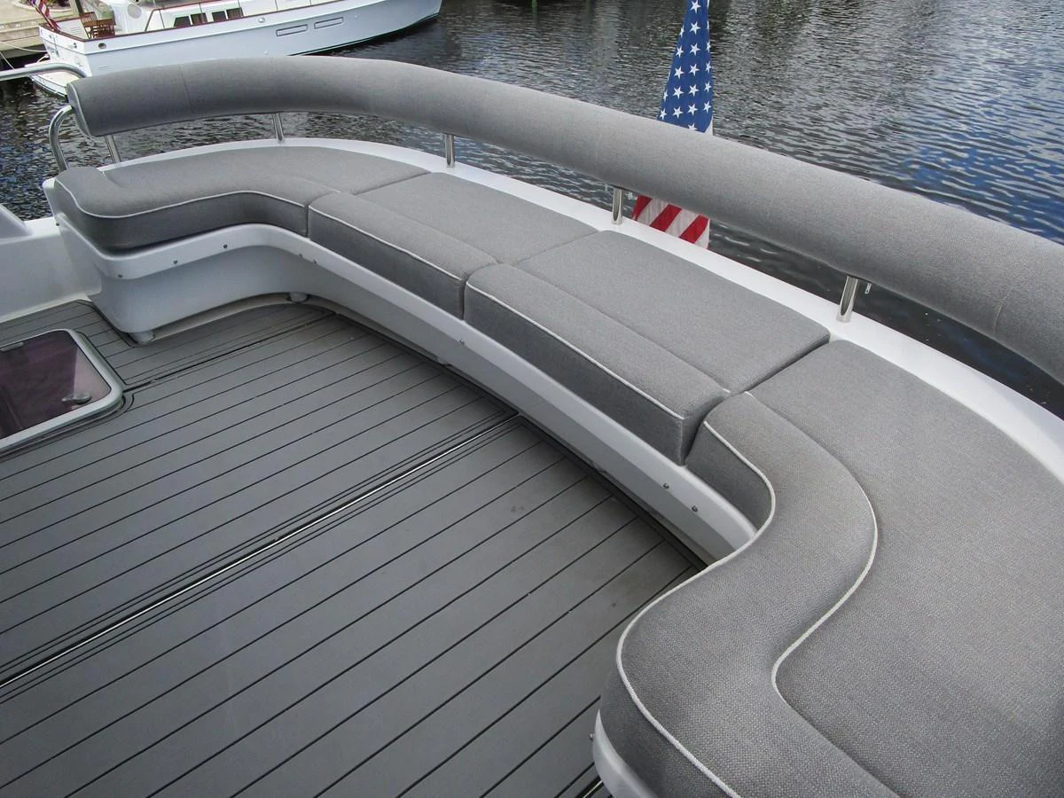 The aft deck features a spacious and comfortable curved seating area with grey cushions, perfect for relaxation. aboard SHORE GIRL Yacht for Sale