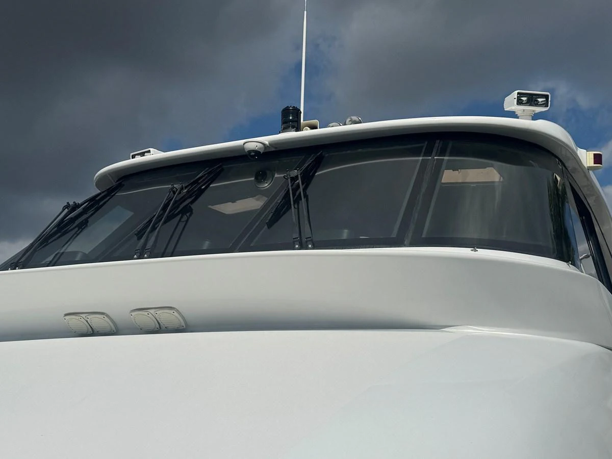 A close-up view of the yacht's helm station and windshield under a cloudy sky. aboard SHORE GIRL Yacht for Sale