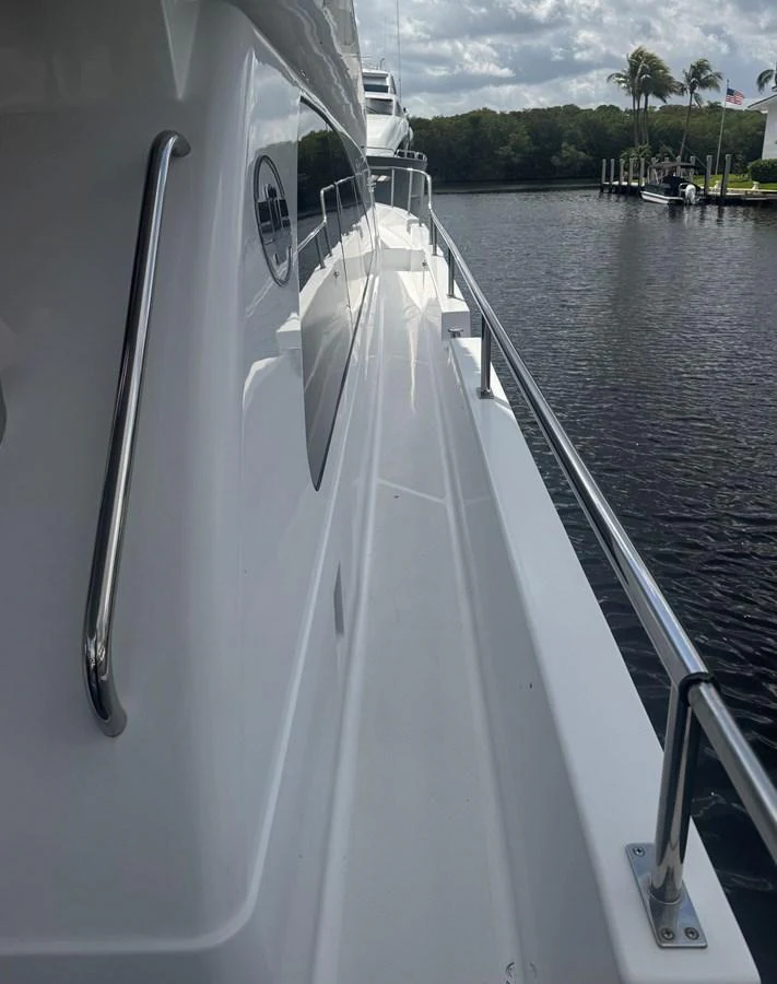 A view of the yacht's side deck with stainless steel handrails and a serene water backdrop. aboard SHORE GIRL Yacht for Sale
