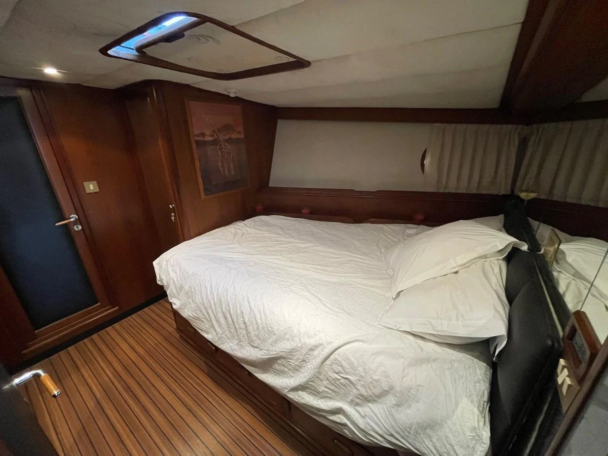 A cozy stateroom featuring a comfortable bed with white linens and wooden accents. aboard ATB MAROC  CUSTOM MOTOR YACHT Yacht for Sale