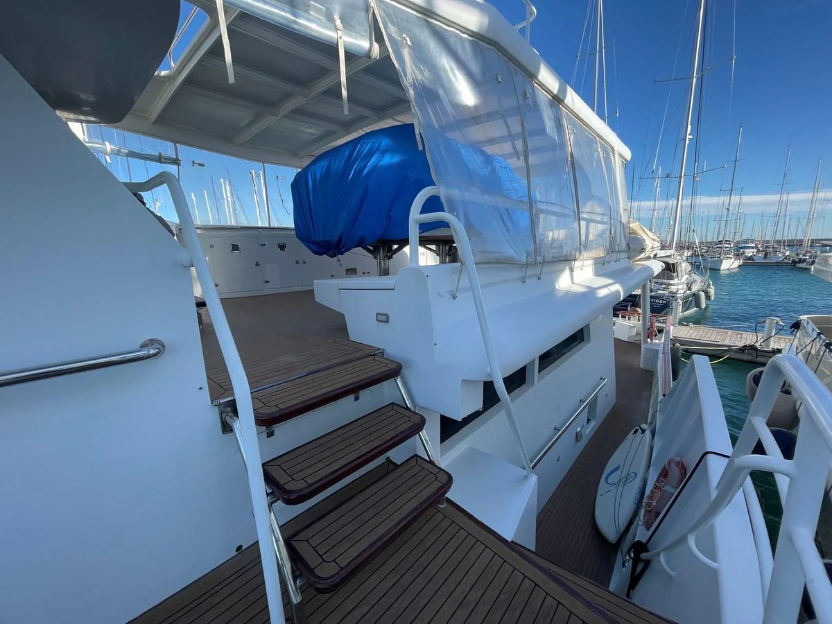The aft deck features a staircase leading up to a covered area, with a view of the marina in the background. aboard ATB MAROC  CUSTOM MOTOR YACHT Yacht for Sale