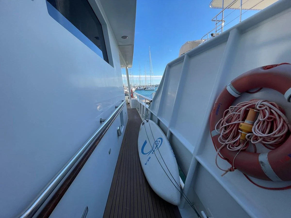 A narrow passageway on the yacht features a surfboard and a life ring, highlighting practical storage solutions. aboard ATB MAROC  CUSTOM MOTOR YACHT Yacht for Sale