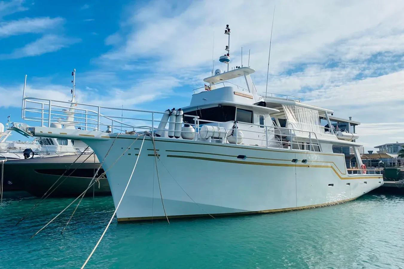 A sleek yacht is docked in a serene marina under a partly cloudy sky. aboard ATB MAROC  CUSTOM MOTOR YACHT Yacht for Sale