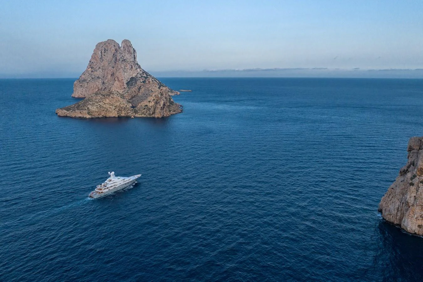 a boat in the water with Roques de Anaga in the background aboard ROCINANTE Yacht for Sale