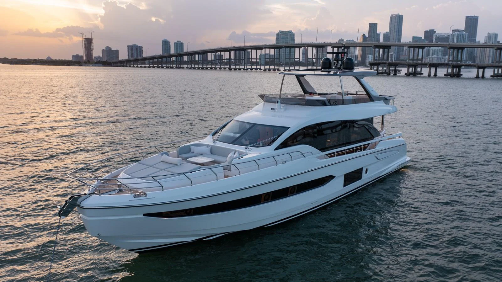 A sleek and modern yacht cruises gracefully on the water with a cityscape in the background. aboard EUPHORIA Yacht for Sale