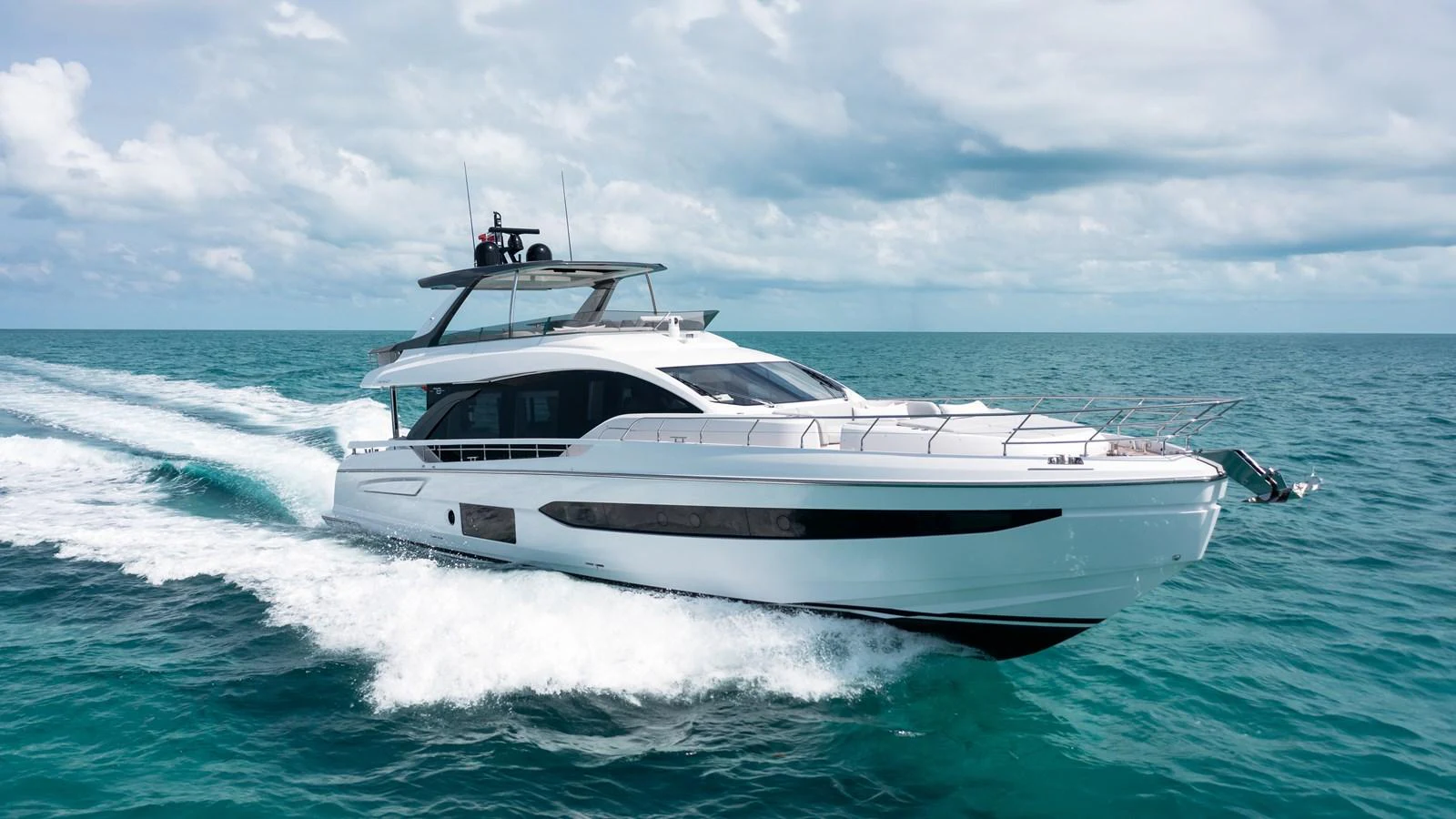 A sleek and modern yacht cruises swiftly across the open sea under a partly cloudy sky. aboard EUPHORIA Yacht for Sale