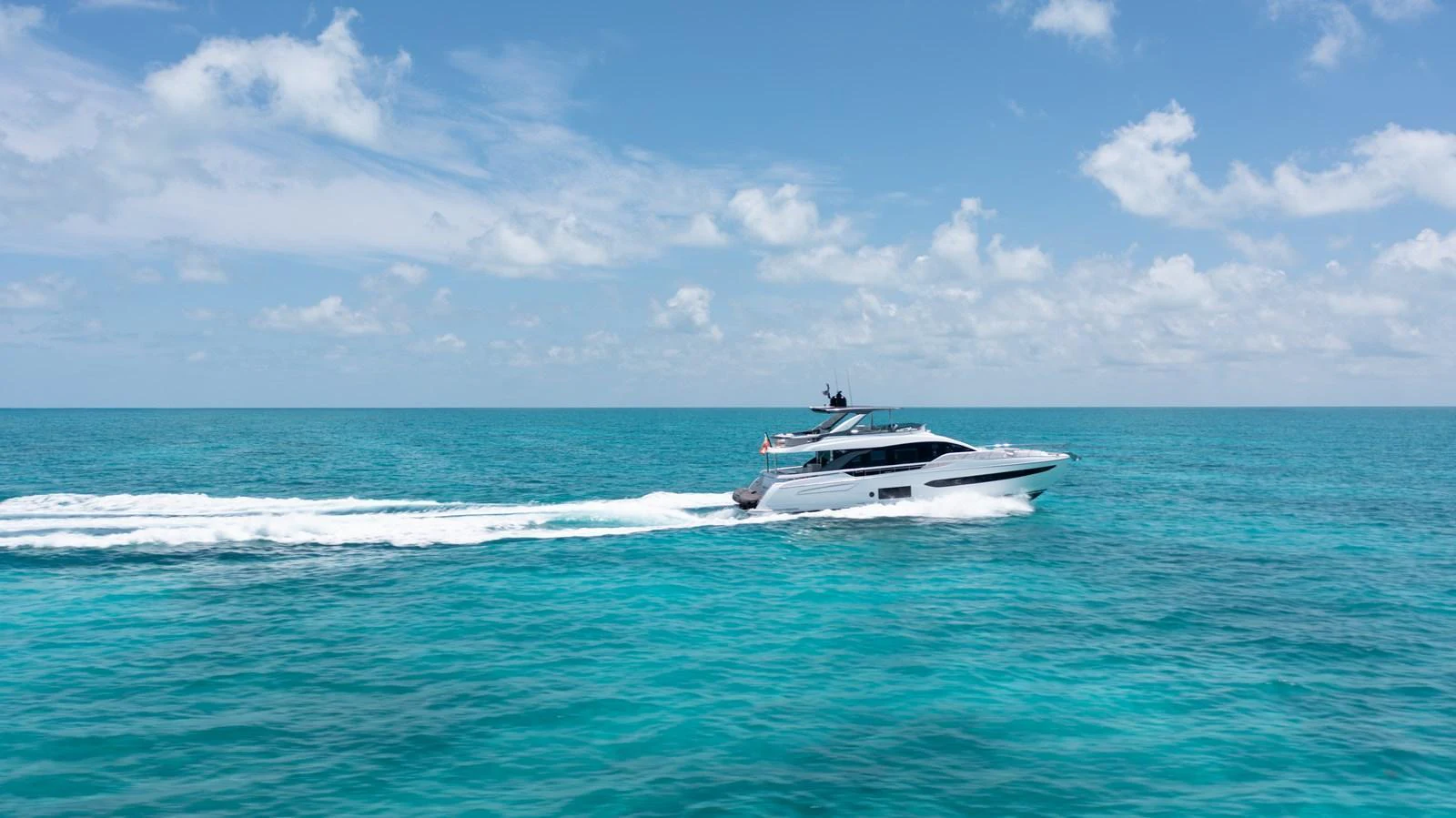A sleek yacht cruises through clear turquoise waters under a bright blue sky. aboard EUPHORIA Yacht for Sale
