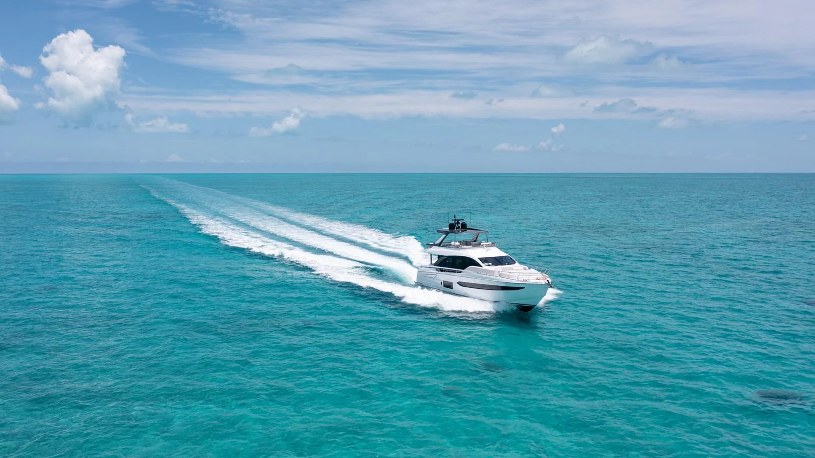 A sleek yacht cruises swiftly through the turquoise waters under a clear blue sky. aboard EUPHORIA Yacht for Sale