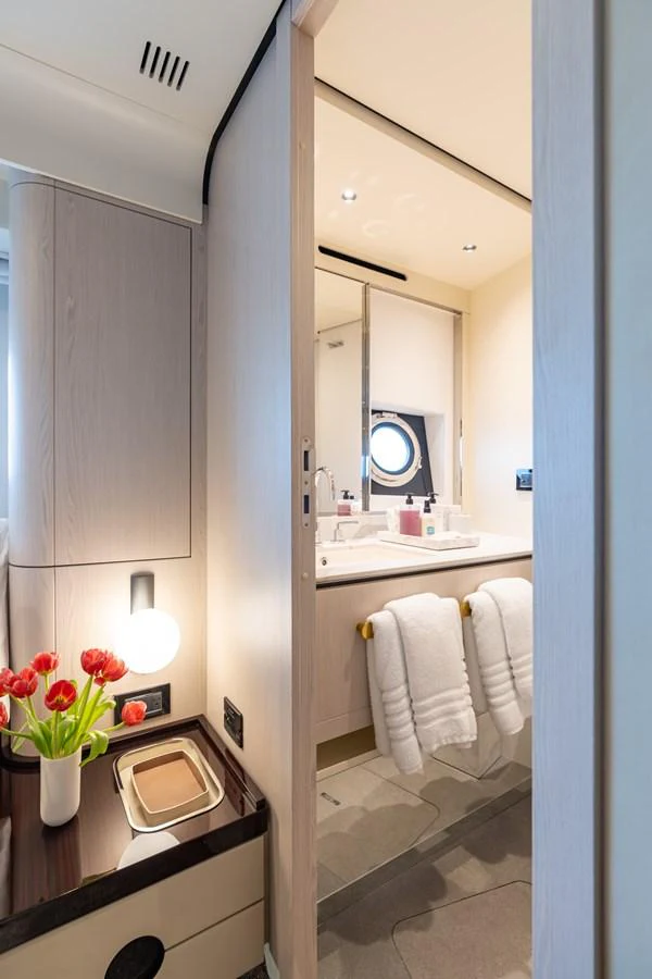 A modern yacht bathroom featuring a sink, towels, and a porthole window. aboard EUPHORIA Yacht for Sale