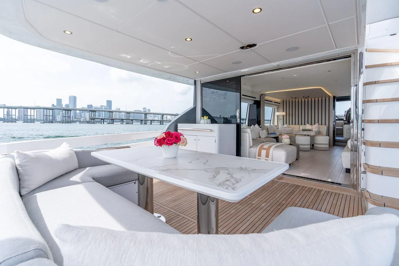 The aft deck features a luxurious seating area with a marble table, seamlessly transitioning into the elegant interior lounge. aboard EUPHORIA Yacht for Sale