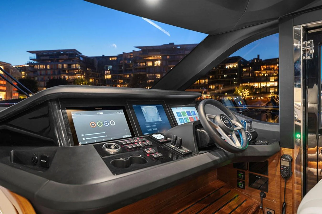 The helm of the yacht features advanced navigation equipment and a luxurious steering wheel, set against a backdrop of a marina at dusk. aboard PRINCESS S72 Yacht for Sale
