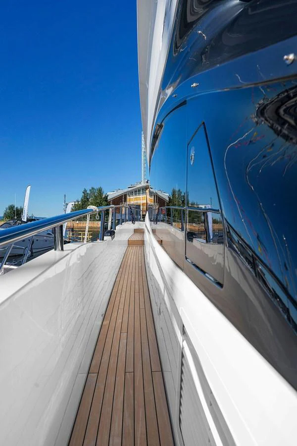 A sleek side deck with polished railings and a wooden walkway, reflecting the clear blue sky. aboard PRINCESS S72 Yacht for Sale