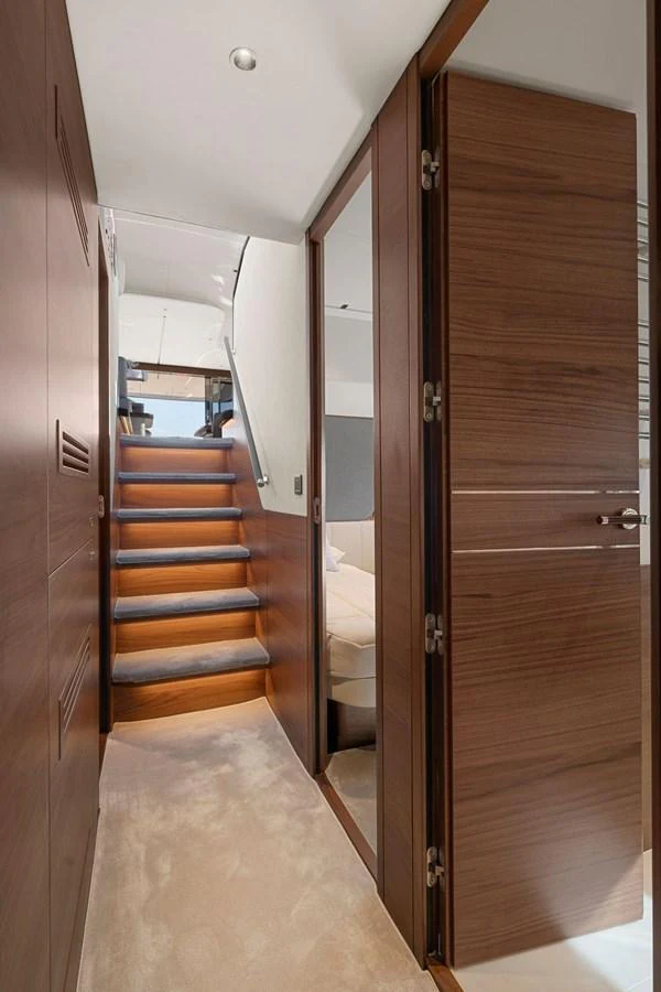 A well-lit interior stairway with wooden finishes leads to the upper deck. aboard PRINCESS S72 Yacht for Sale